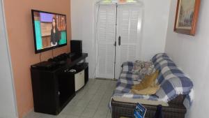 salon z kanapą i telewizorem z płaskim ekranem w obiekcie Linda Suíte perto da Praia do Forno w mieście Arraial do Cabo