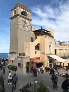 un edificio con una torre de reloj con gente caminando alrededor en Piazzetta House, en Capri