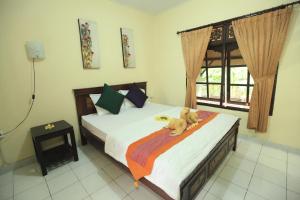 a teddy bear laying on a bed in a bedroom at Liang House and Hostel in Ubud