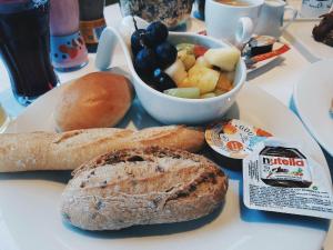 a plate of food with bread and a bowl of fruit at Biznis Hotel in Lokeren