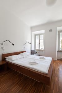 a bedroom with a large bed and two windows at Julija&Robert's Riverview Apartments and Rooms in Ljubljana
