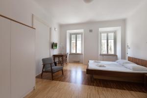 a white bedroom with a bed and a chair at Julija&Robert's Riverview Apartments and Rooms in Ljubljana
