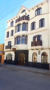 a large white building with balconies on a street at Hostal La Magia de Uyuni in Uyuni