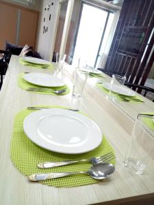 a table with white plates and silverware on a green napkin at NEW CONDO UNIT@PALMTREE VILLAS NEAR NAIA3 in Manila