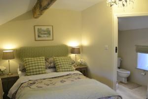 a bedroom with a bed with a green headboard and two lamps at Birkend Farmhouse in Feetham