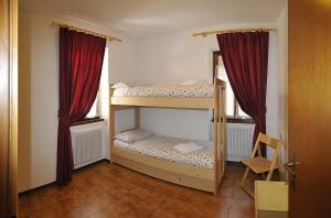 2 Etagenbetten in einem Zimmer mit roten Vorhängen in der Unterkunft Casa Civetta in Massimeno