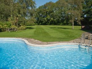a swimming pool in front of a yard with a park at Silverland in Hordle