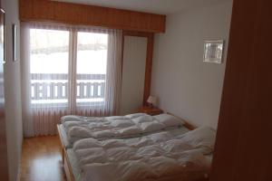 two beds in a room with a large window at appartement dans le centre thermal les Sources Ovronnaz in Ovronnaz