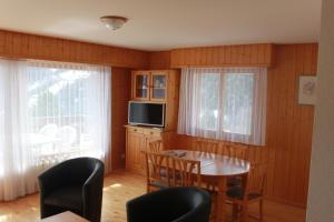 a dining room with a table and chairs and a television at appartement dans le centre thermal les Sources Ovronnaz in Ovronnaz