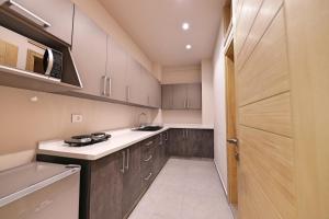 una cocina con encimeras blancas y armarios de madera en The Residence 649 en An Naqqāsh