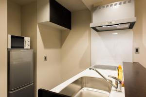 una cocina con fregadero y refrigerador en INOVA Kanazawa, en Kanazawa