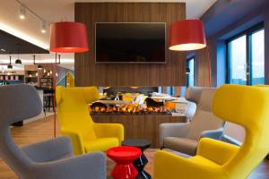 a lobby with yellow chairs and a fire place at ibis Styles Haarlem City in Haarlem