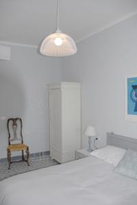 a white bedroom with a bed and a chair at La Nipitella in Montemarcello