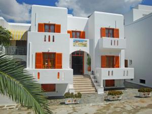 a white house with orange shutters and a palm tree at Vassiliki Rooms in Parikia