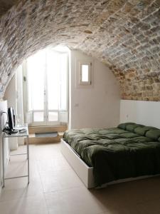a bedroom with a bed and a brick wall at Specula Domus - Ibla in Ragusa