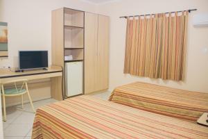 a hotel room with two beds and a desk at Plaza Dutra Hotel in Caçapava