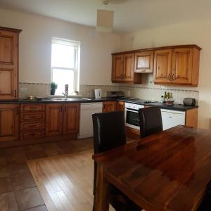 uma cozinha com armários de madeira e uma mesa de madeira em 7 Doolin Court em Doolin