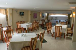 una sala da pranzo con tavoli e sedie bianchi e un cercapersone di Hotel Feni a Kavadarci