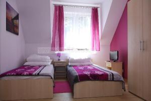two beds in a room with pink walls and a window at Dom Sandi Dziwnowek in Dziwnówek