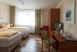 a hotel room with two beds and a desk at Hotel Monopol in Gelsenkirchen