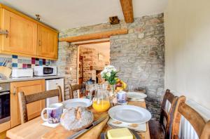 a kitchen with a wooden table with bread on it at Abereithrin Cottage in Pentre-bâch