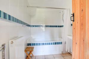 a white bathroom with a tub and a wooden chair at Abereithrin Cottage in Pentre-bâch +32 photos