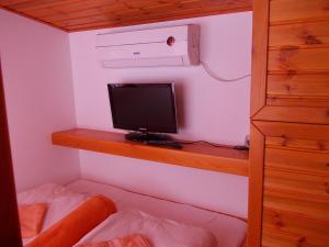 a computer monitor sitting on a wooden shelf in a bedroom at Minilux Studio in Berekfürdő