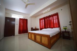 a bedroom with a bed and red curtains at Indeevaram Residency in Trivandrum