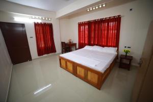 a bedroom with a large bed and red curtains at Indeevaram Residency in Trivandrum