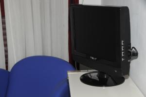 un monitor de ordenador sentado en un escritorio con una silla azul en Hostal Sierra, en San Sebastián de los Reyes