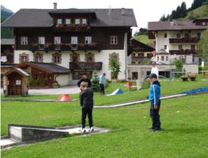 dos chicos parados en un campo frente a una casa en Pension Kröll en Sankt Jakob in Defereggen