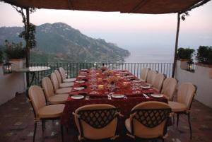 a long table with chairs and a view of the ocean at Hotel Parsifal - Antico Convento del 1288 in Ravello
