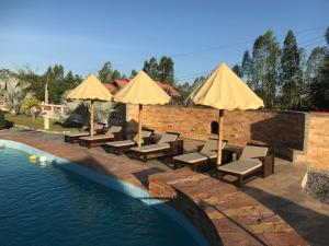 a pool with chairs and umbrellas next to the water at The Orchid Resort & Relax in Maha Sarakham