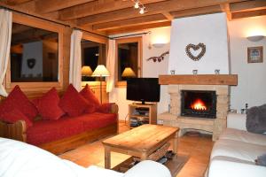 a living room with a red couch and a fireplace at Chalet Orlando in Les Gets