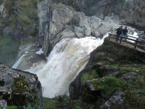 dos personas de pie en un puente sobre una cascada en Pensión El abuelo, en Carbellino