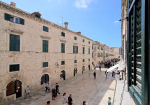 a group of people walking in a street next to a building at Dreams Stradun Apartments in Dubrovnik