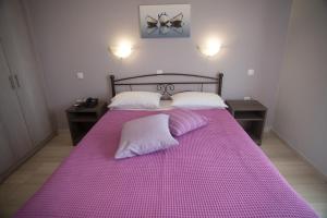 a purple bed with two white pillows on it at Galazio Limani - Rooms to let in Moúdhros
