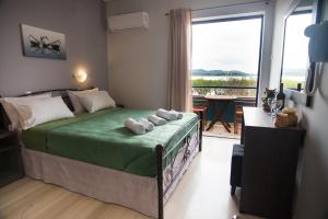 a bedroom with a bed with a green blanket and a window at Galazio Limani - Rooms to let in Moúdhros