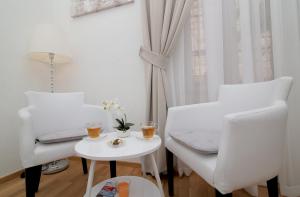 a white living room with two chairs and a table at Dreams Stradun Apartments in Dubrovnik