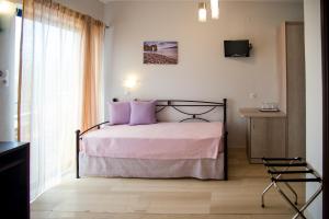 a bedroom with a bed with purple pillows and a window at Galazio Limani - Rooms to let in Moúdhros