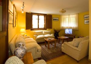 a living room with couches and a tv at La Casona de Mestas in Ponga