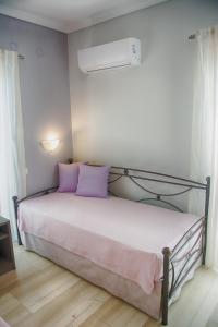 a bedroom with a bed with purple pillows at Galazio Limani - Rooms to let in Moúdhros