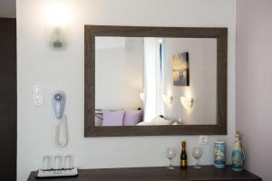 a mirror on a wall above a table with wine glasses at Galazio Limani - Rooms to let in Moúdhros