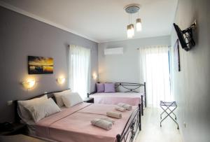 two beds in a bedroom with pink sheets at Galazio Limani - Rooms to let in Moúdhros