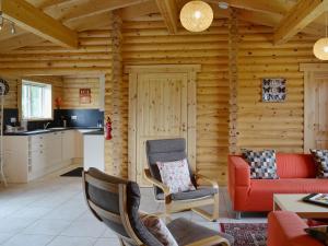 a log cabin living room with a red couch and chairs at Quail Lodge - W44304 in Burn