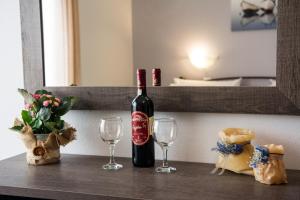 a bottle of wine and two glasses on a table at Galazio Limani - Rooms to let in Moúdhros