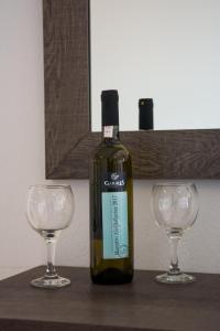 a bottle of wine sitting between two wine glasses at Galazio Limani - Rooms to let in Moúdhros