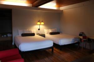 una habitación de hotel con 2 camas y una silla roja en Timbers Inn, en Eugene