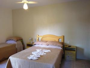 a bedroom with two beds with white flowers on them at Pousada Félix in Nova Petrópolis