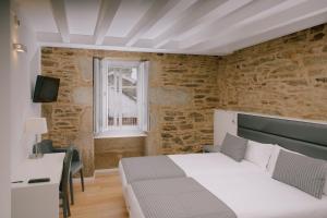 a bedroom with a bed and a desk and a window at Os Sobri&ntilde;os Do Pai in Santiago de Compostela